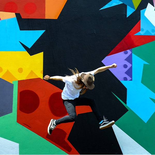 Person jumping against a brightly colored wall